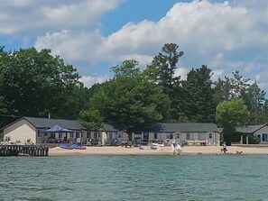 A waterfront hotel with multiple buildings, a sandy beach, and boats. - #5-The Lazy Fish (Au Sable Charter Township)