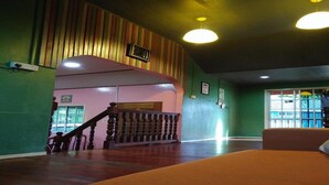 A hotel lobby with a staircase, a clock, and a remote control on a table. - OYO 90195 Anjung Rehat Jamsari (Ranau)