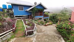 A blue house with a satellite dish, surrounded by gardens and a concrete path. - OYO 90195 Anjung Rehat Jamsari (Ranau)