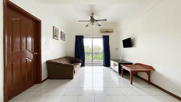A spacious living area with a brown door, a brown sofa, a wooden table, and a ceiling fan.