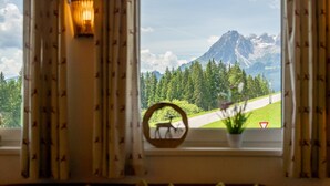 A window with a view of a mountain landscape, curtains, and a wall-mounted light fixture.