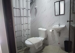 A bathroom with a toilet, a sink, and a shower. - Lolas Lodge (Boracay Island)