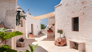 A courtyard with stone buildings, potted plants, and a bicycle. - Trulli residence with private pool close to Locorotondo (Puglia)
