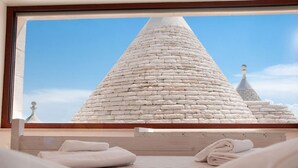 A hotel room with a large window overlooking a stone structure. - Trulli residence with private pool close to Locorotondo (Puglia)