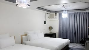 Et hotelværelse med to senge, et skrivebord, en lampe og udsigt til det fri.