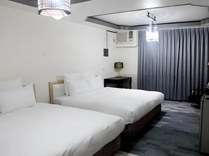 Ett hotellrum med två sängar, ett skrivbord, en lampa och utsikt över omgivningarna.