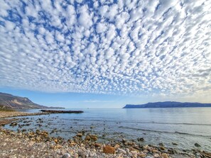 Une côte rocheuse offrant une vue dégagée sur l’eau et les montagnes lointaines.