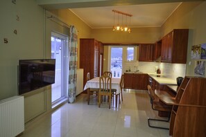 Una cocina con armarios de madera, una mesa de comedor con sillas, horno empotrado y un ventanal grande.