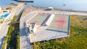 Ett flygbildsfoto av ett sportkomplex med flera banor, en simbassäng och ett läge vid stranden.