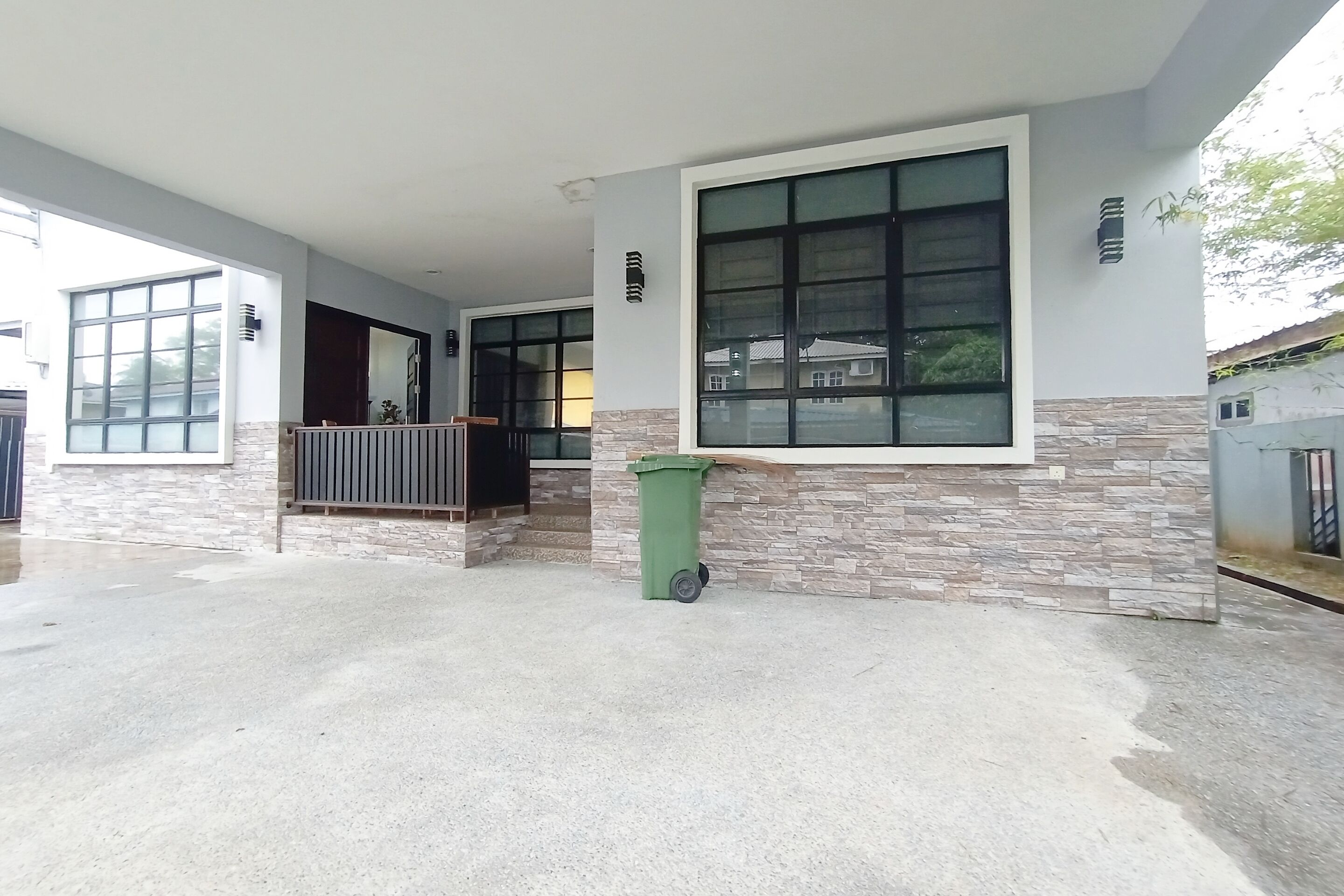 A building with large windows, a stone facade, and a green trash bin.