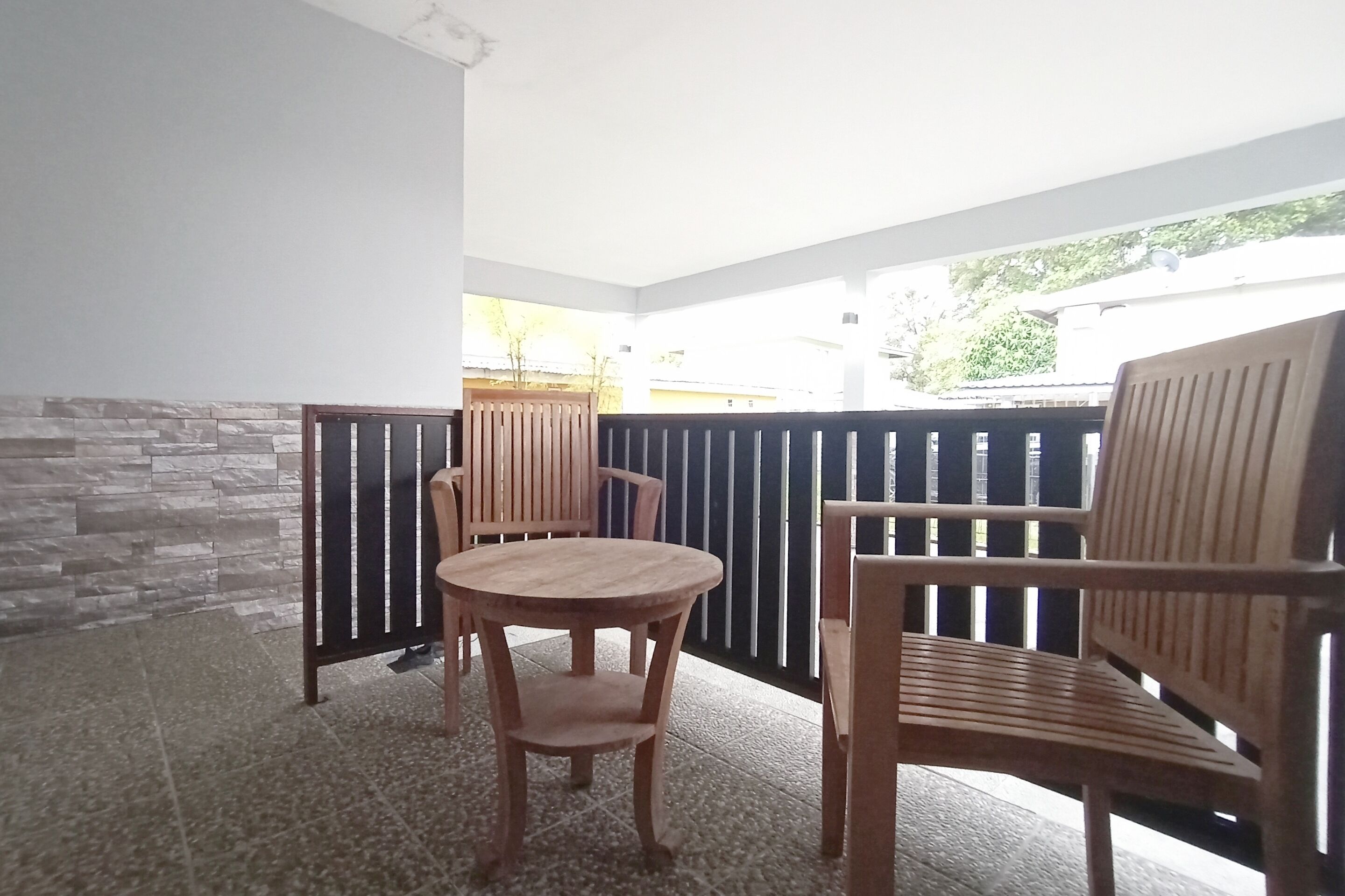 A balcony with a round wooden table and two wooden chairs.
