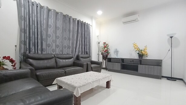 A living room with a grey sofa, a coffee table, and a cabinet. - OYO 90203 Emma Sukma Homestay (Kuching)