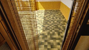 Un pasillo con piso de cuadros, pared amarilla y blanca, y una cortina dorada decorativa.