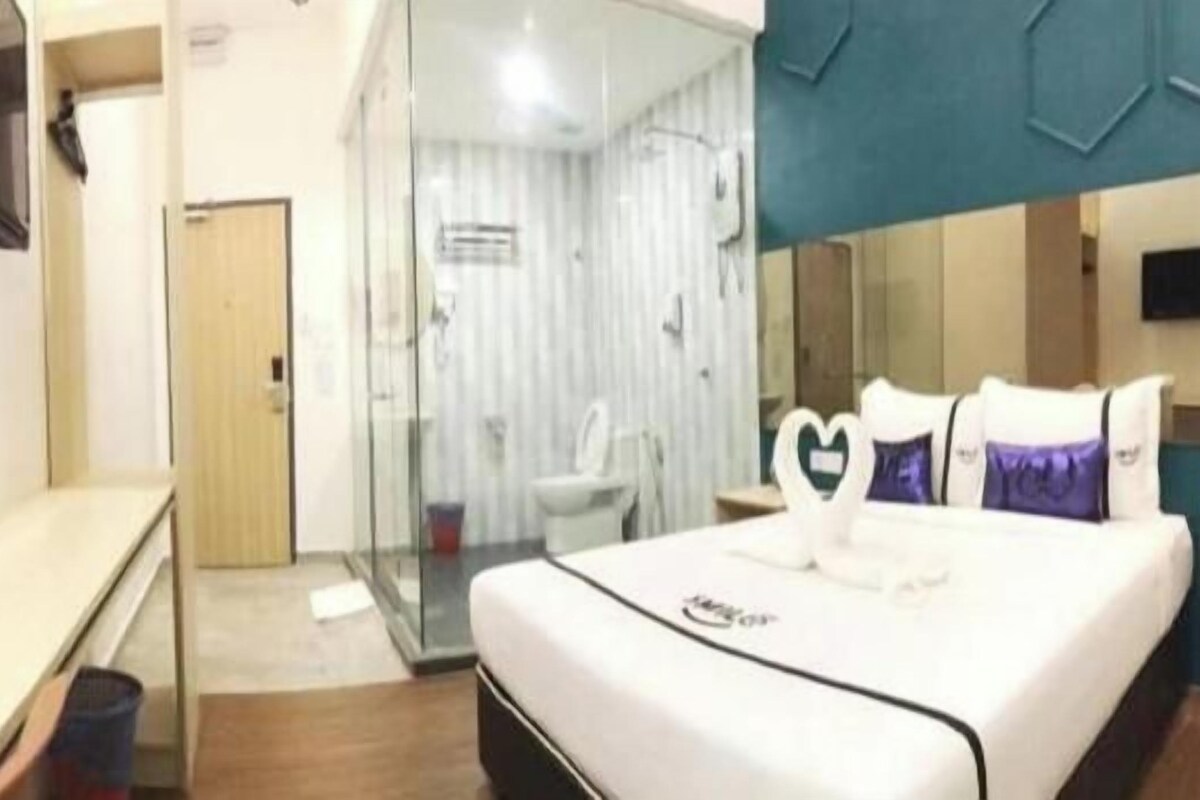 Une chambre d’hôtel équipée d’un lit, d’un bureau, d’une télévision et d’un espace douche.