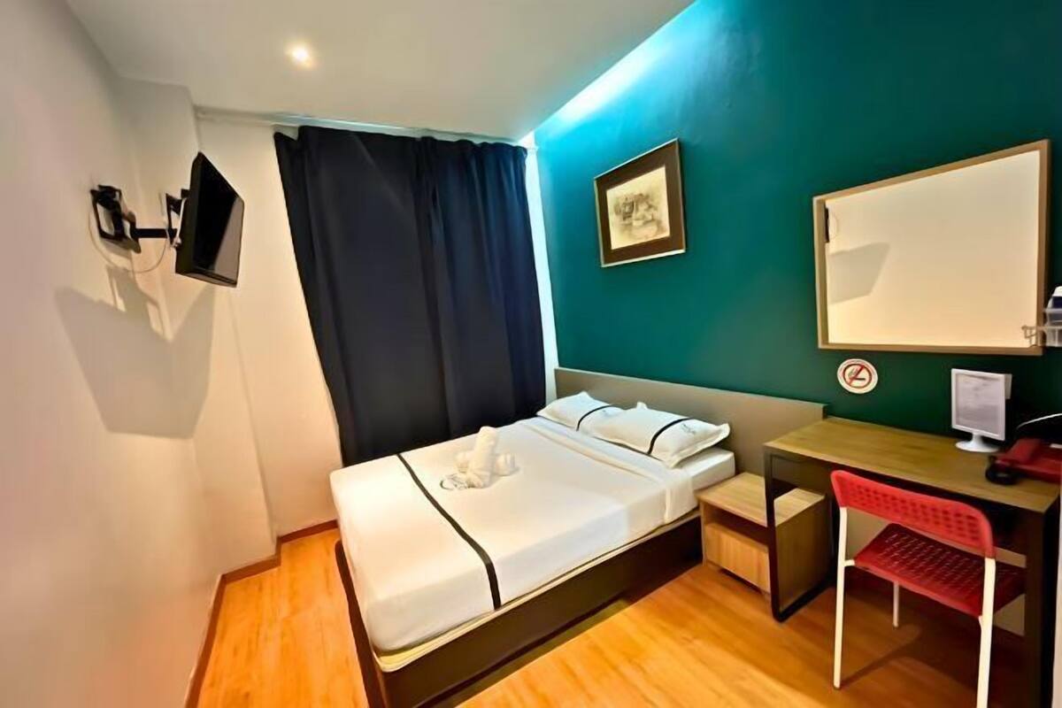 Une chambre d’hôtel équipée d’un lit, d’un bureau, d’une chaise, d’un téléviseur, d’un tableau encadré et d’un écran d’ordinateur.