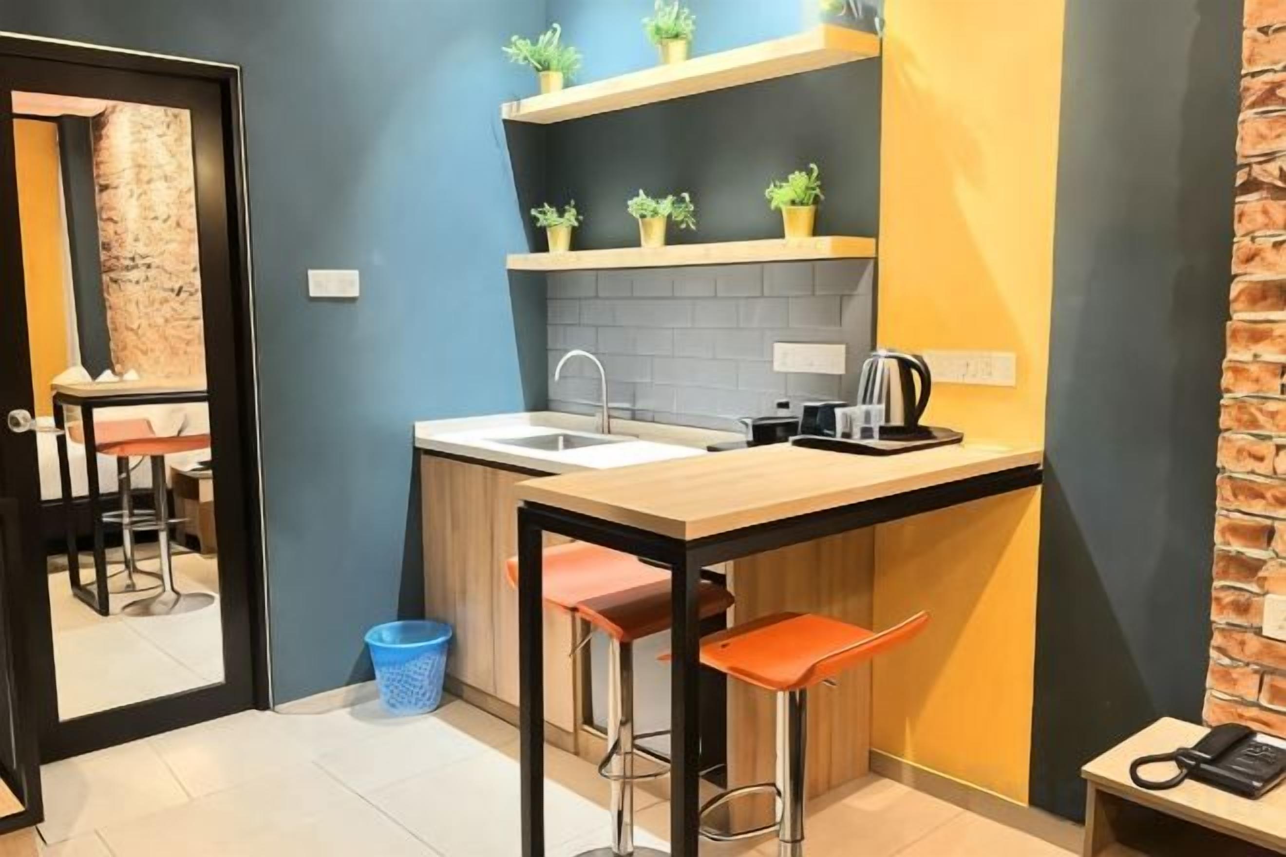 A compact kitchen with a sink, countertop, and stools.