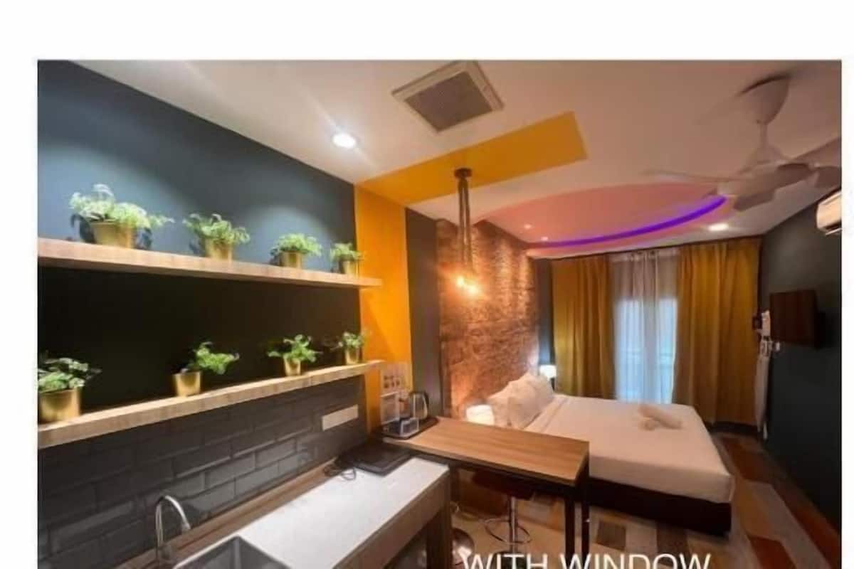 Une chambre d’hôtel de taille réduite, dotée d’une kitchenette, d’un lit et d’une fenêtre.