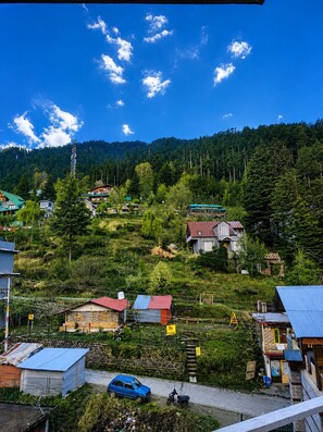A mountainous village with houses, a car, and a clear blue sky. - Nirvana Hills (Manali)