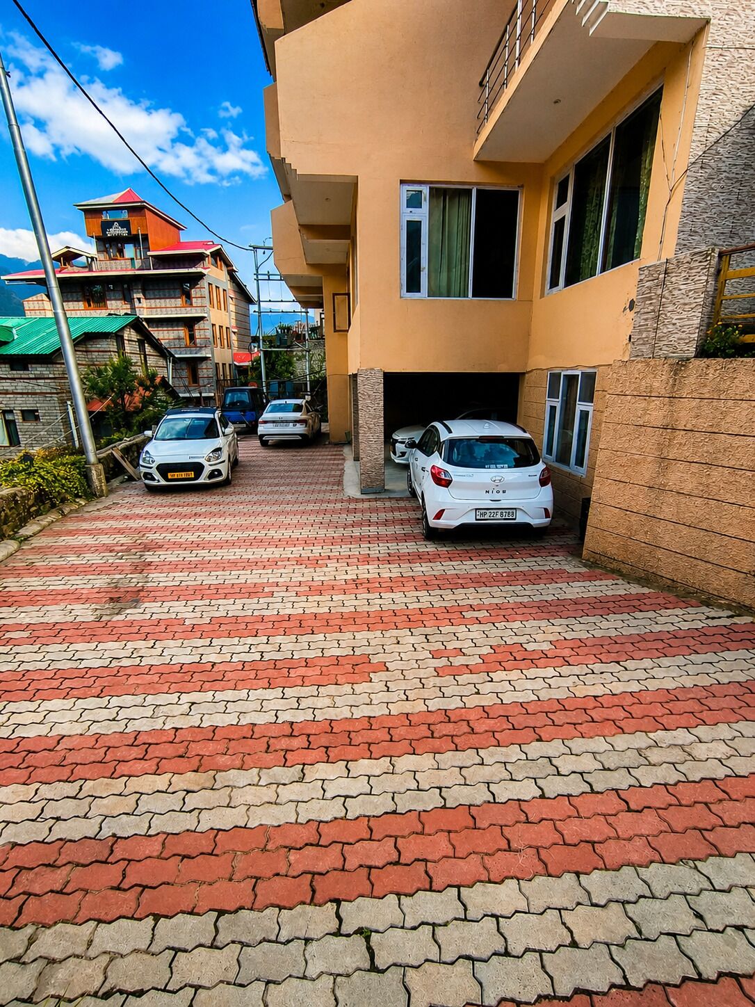 Eine Wohnstraße mit parkenden Autos und einem mehrstöckigen Gebäude mit Balkonen.