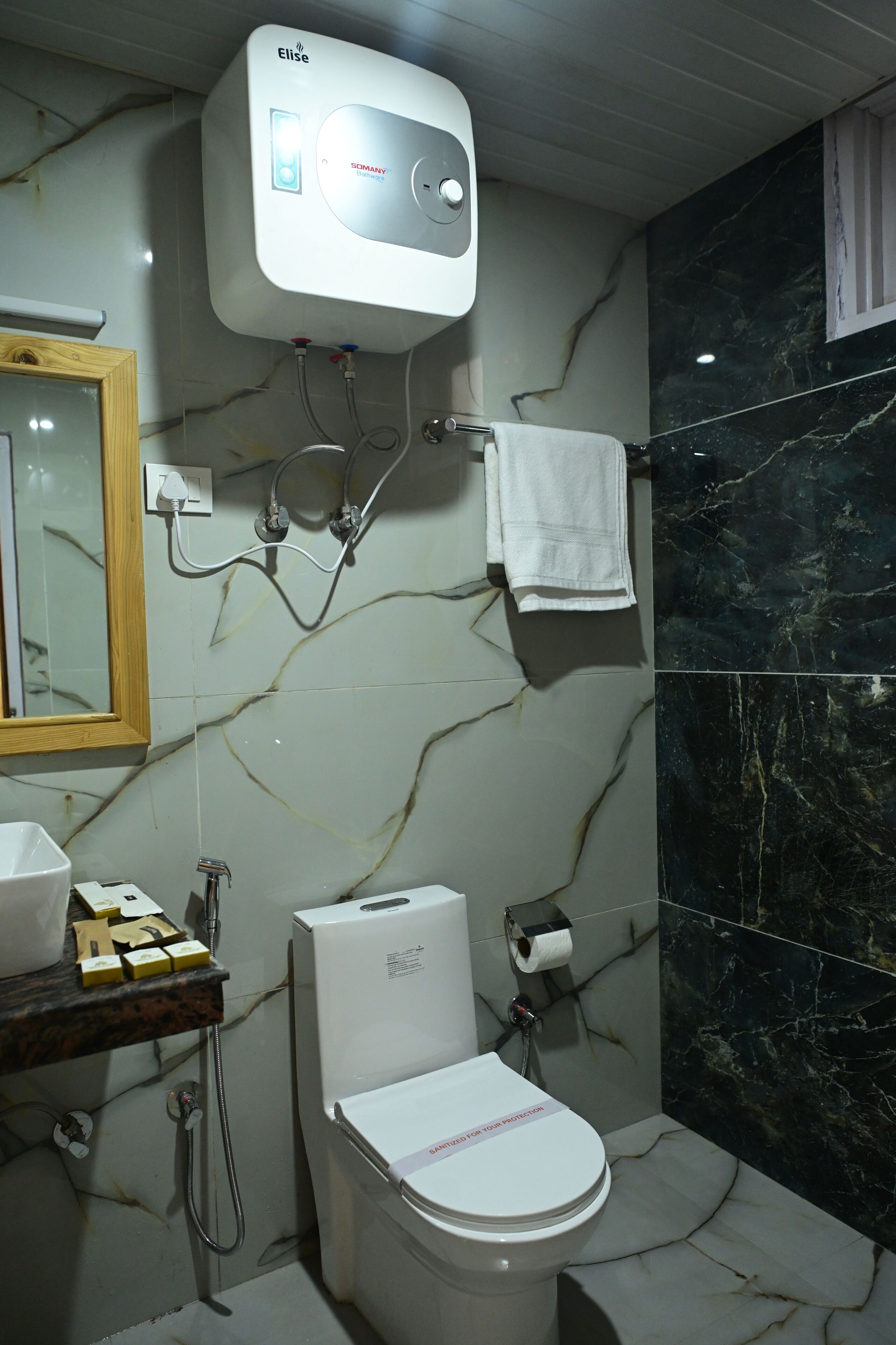 A bathroom with a toilet, a sink, a mirror, a towel rack, and a water heater.