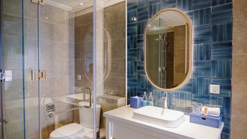 A modern bathroom with a glass shower enclosure, a white sink, and a blue-tiled wall.