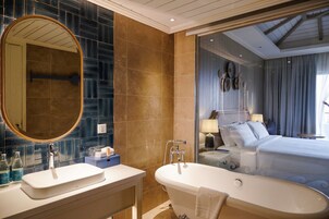 A modern bathroom with a freestanding bathtub, two sinks, and a large mirror.