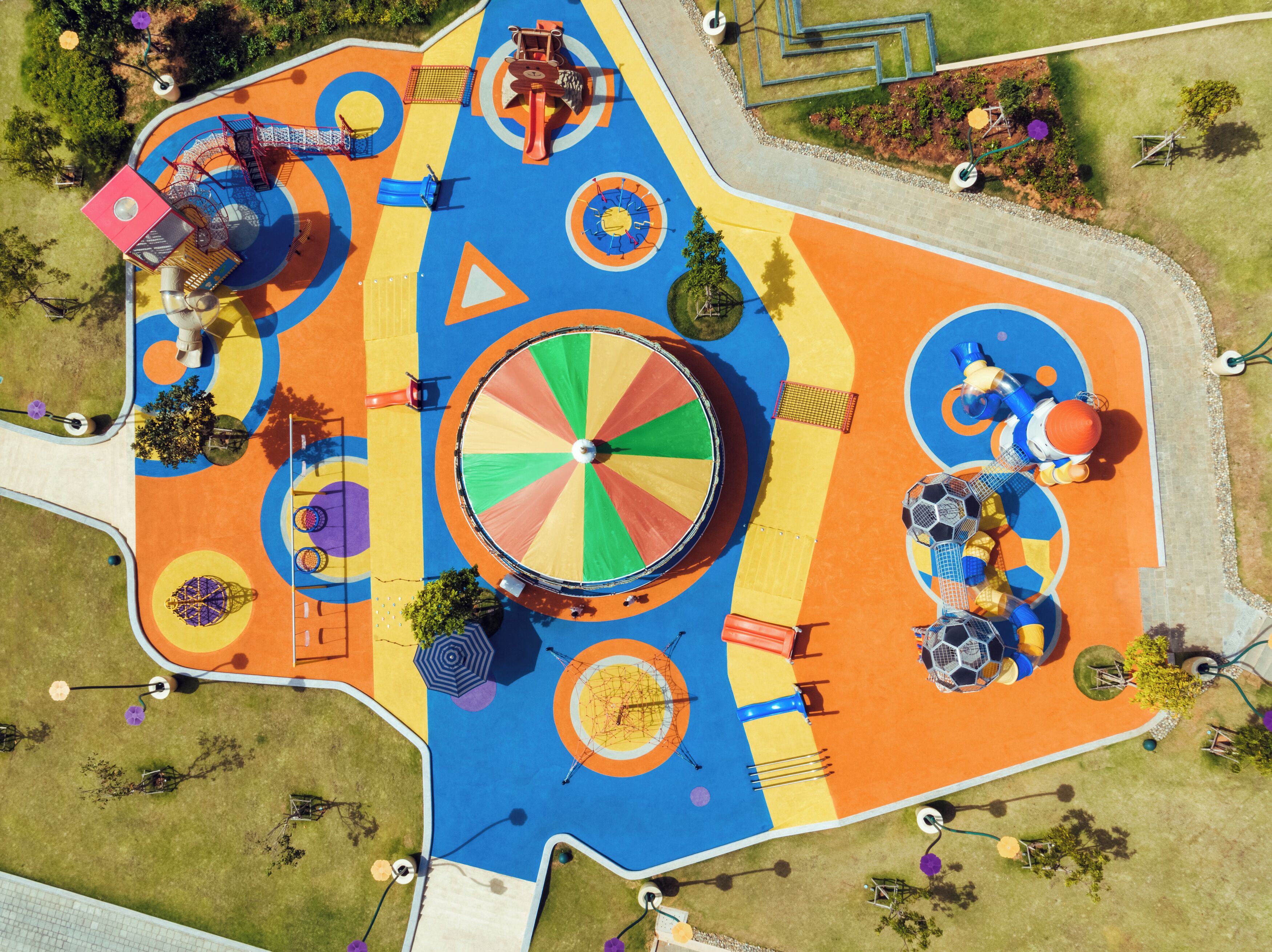 An aerial view of a colorful playground with various play structures, including slides, swings, and climbing areas.