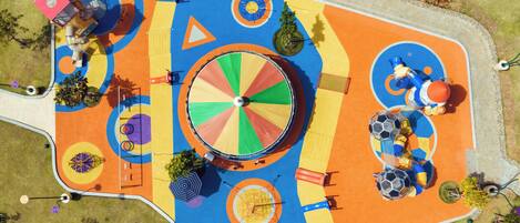 An aerial view of a colorful playground with various play structures, including slides, swings, and climbing areas.