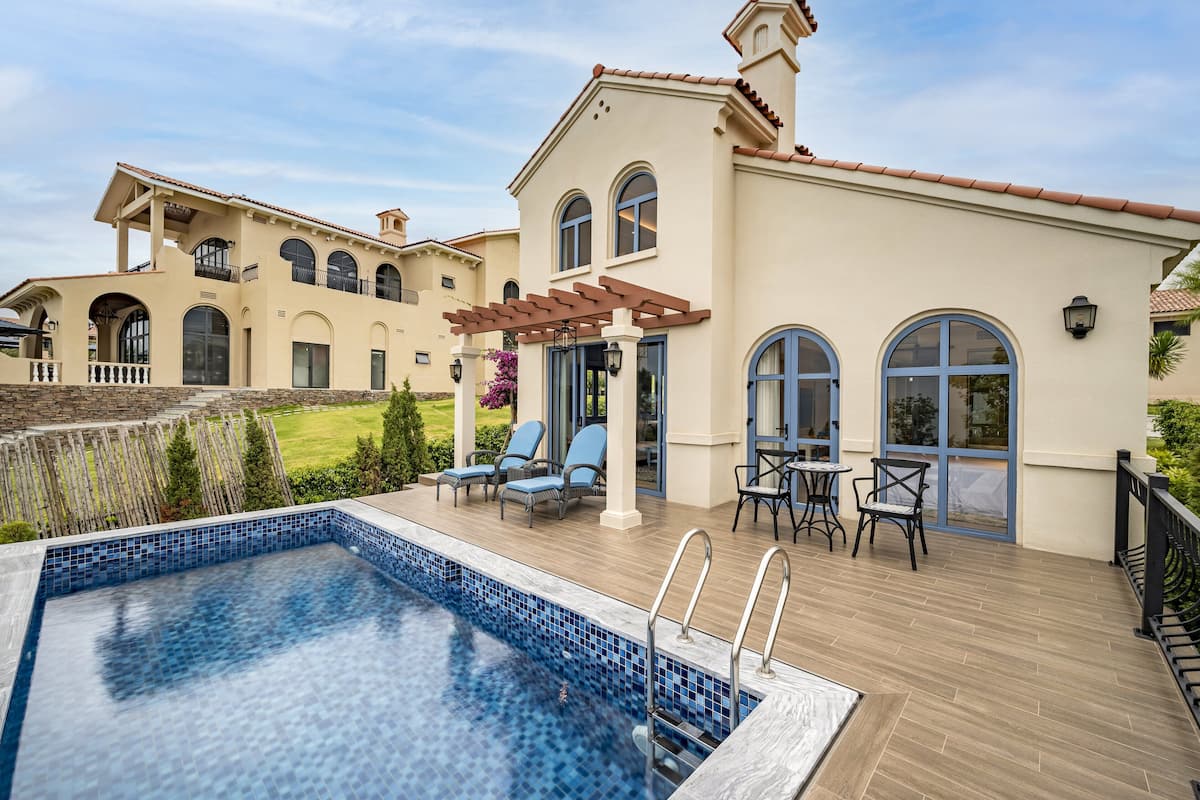 A pool area with a pergola, lounge chairs, and a patio table.