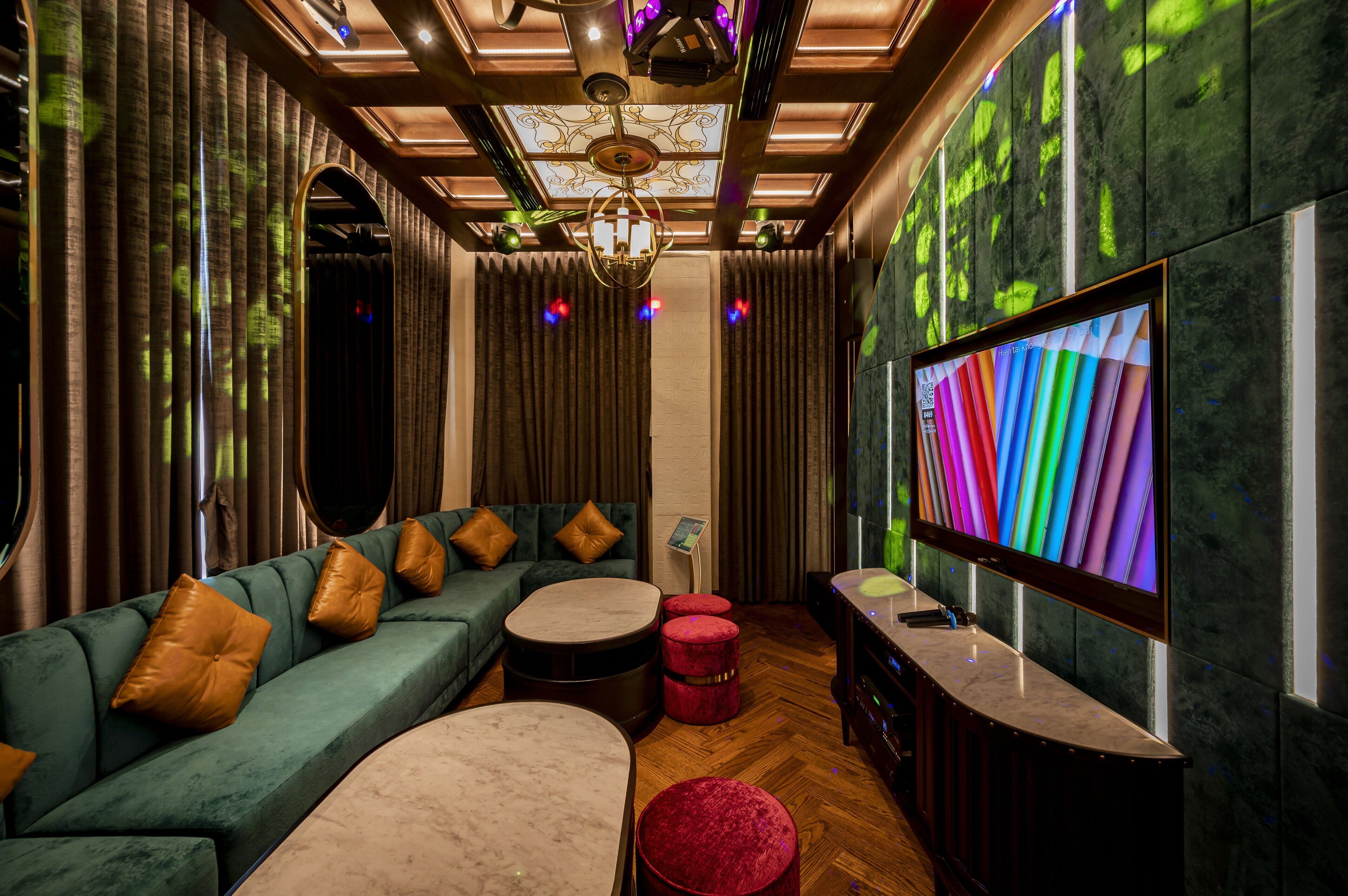 A modern interior with a green sofa, red ottomans, a marble coffee table, and a large flat-screen TV.