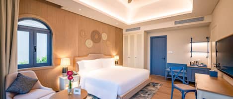 Una habitación de hotel moderna con una cama grande, un escritorio, una silla, un ventilador de techo y un ventanal amplio.