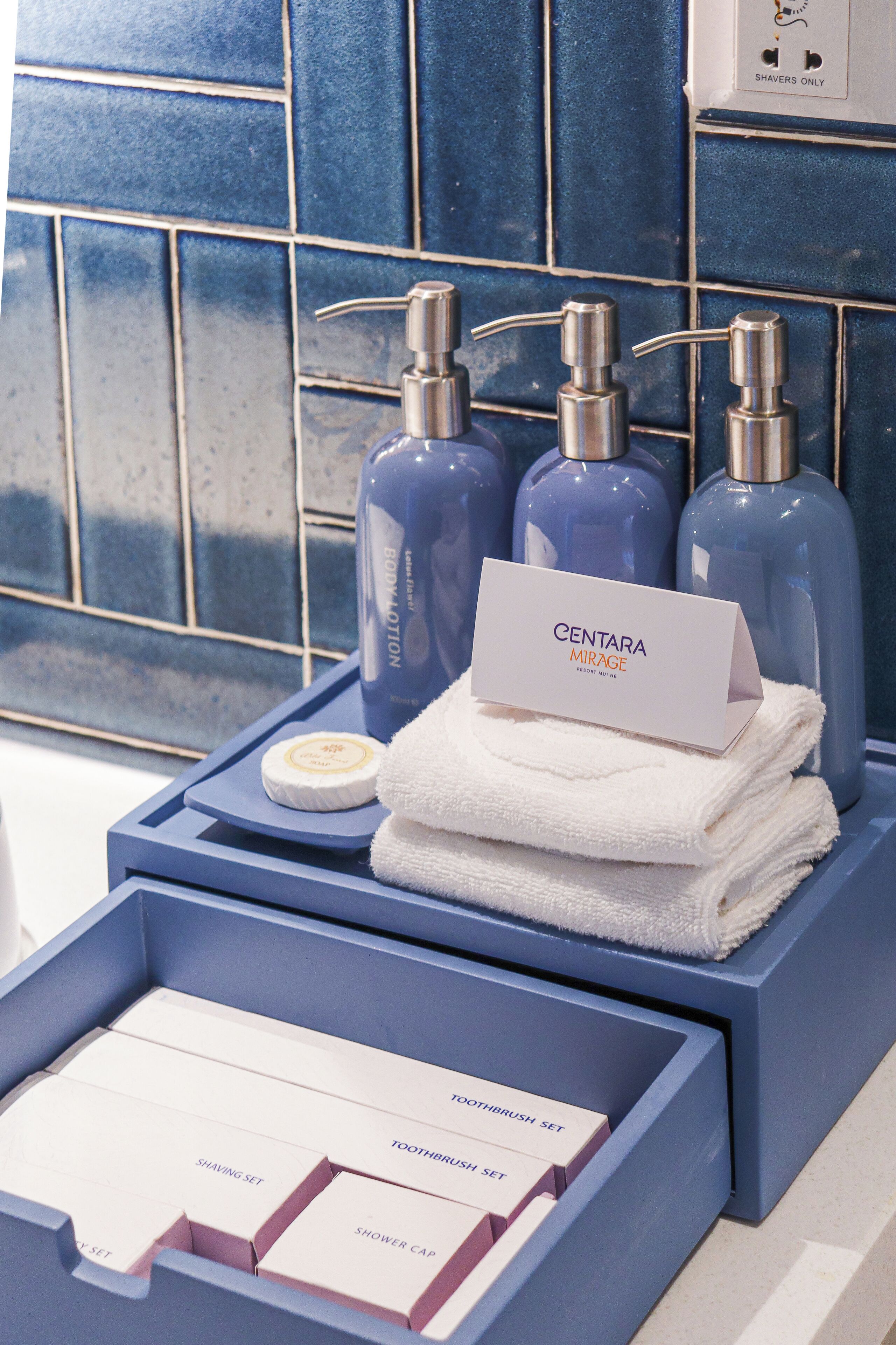 Un tocador de baño con artículos de aseo Centara Mirage, que incluyen un kit de afeitar, un juego de cepillos de dientes y un gorro de ducha.