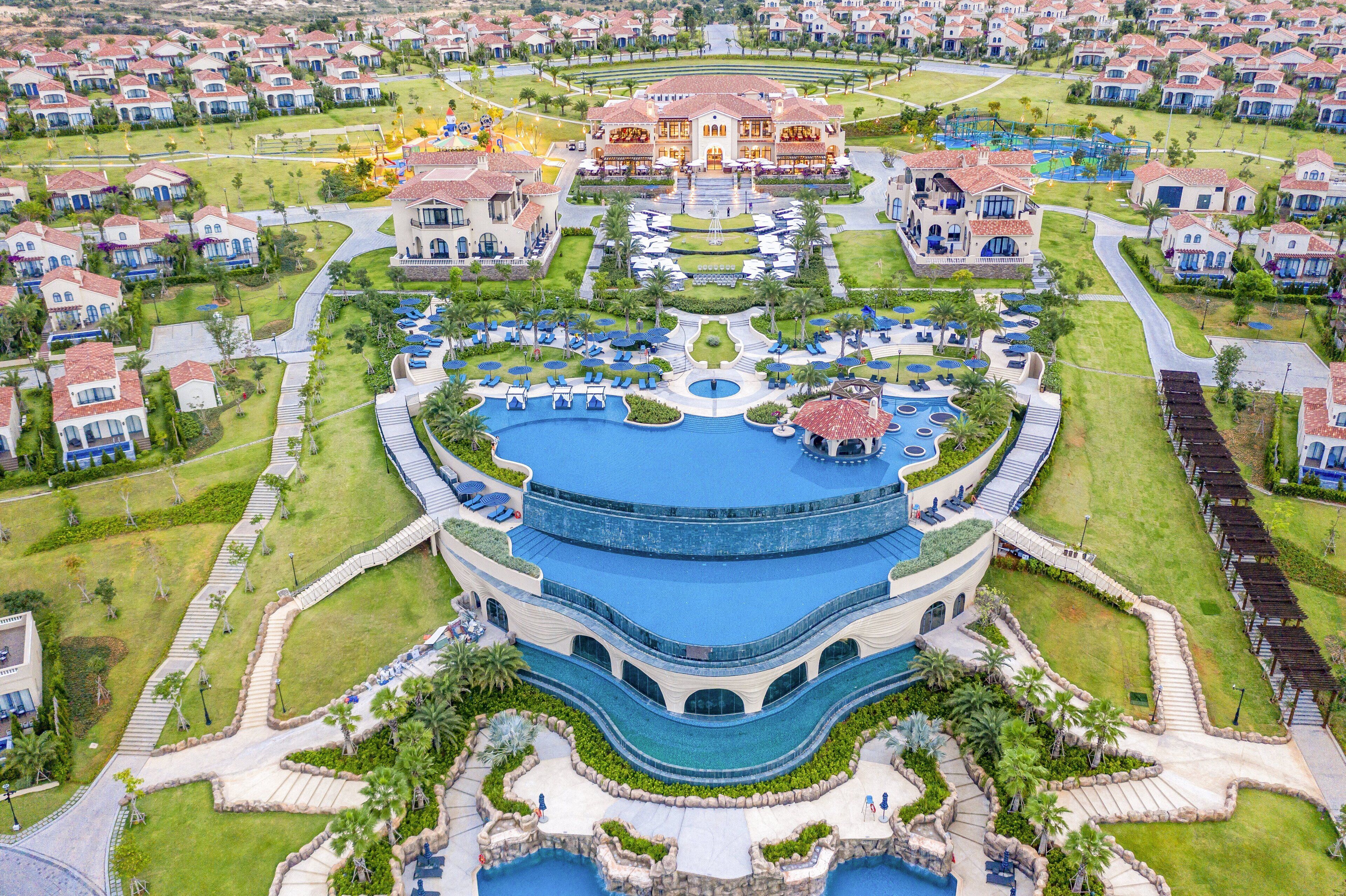 A resort with a central pool, multiple guest villas, and a landscaped garden.