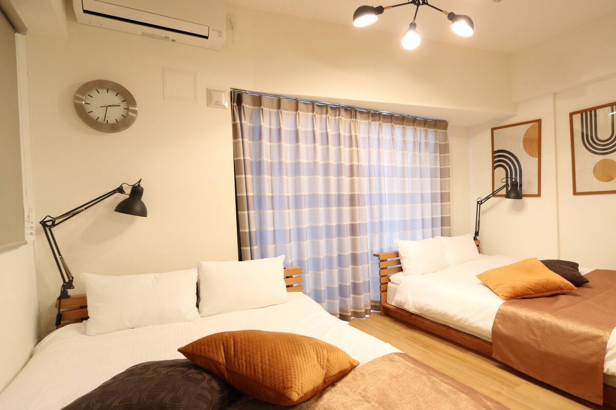 Una habitación de hotel con dos camas, un reloj, una ventana con cortinas y decoración en la pared.
