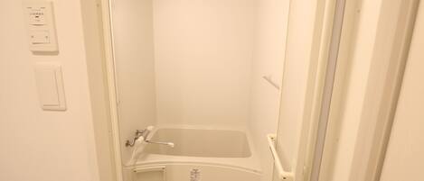 Un baño pequeño y blanco con bañera, inodoro y ducha.