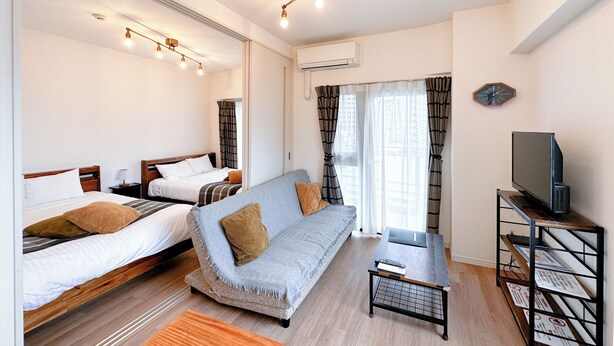 A modern hotel room with two beds, a sofa, a TV on a stand, and a window with curtains. - Legatio HAKATA (Fukuoka)