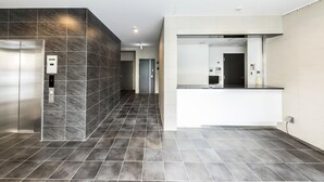 A modern hotel lobby with a marble wall, a reception desk, and a tiled floor. - Legatio HAKATA (Fukuoka)