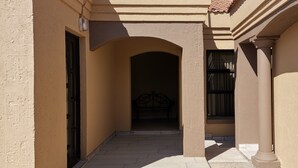 Un estrecho pasillo con un banco, una puerta y una ventana con cortinas.