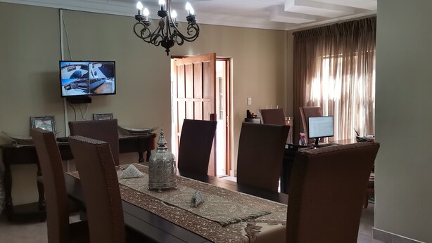 Un comedor con una araña, un televisor montado en la pared y vistas al exterior a través de una puerta.