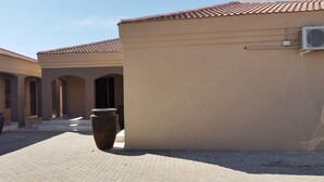 Un patio con techos de tejas, una maceta grande y un edificio de fachada color beige.
