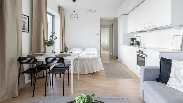 Una habitación moderna y bien iluminada con comedor, cama y kitchenette.