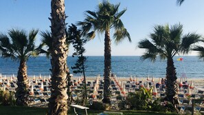 A beach with rows of sun loungers and palm trees. - The Fisherman's House (Sciacca)