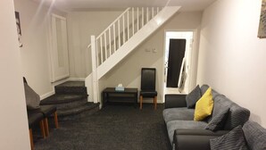 En stue med trappe, en grå sofa og en sort lænestol.