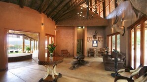 A spacious interior with a high ceiling, a round table with a vase, a sofa, and a large bull head sculpture. - Olievenfontein Private Game Reserve (Vaalwater)