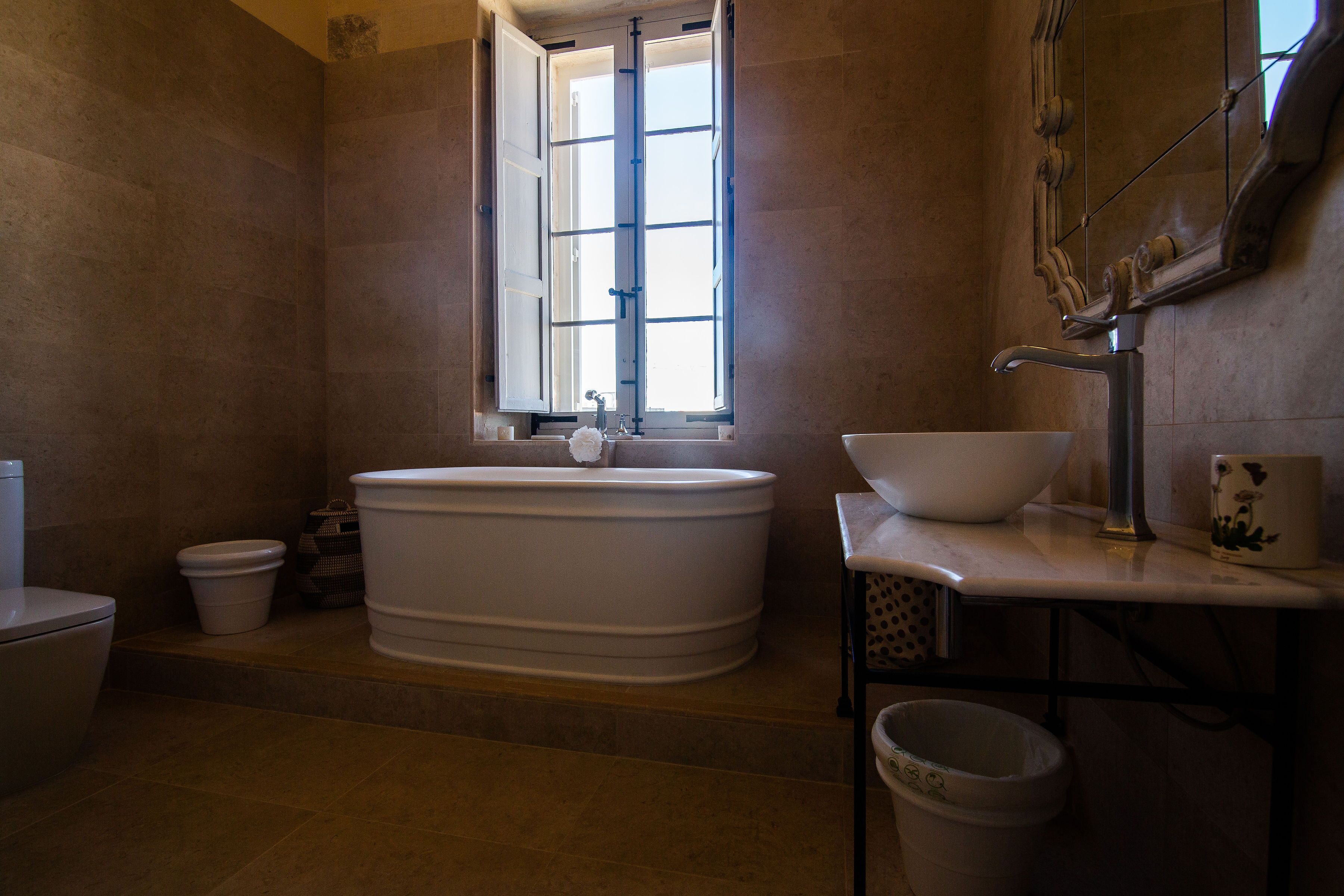 A bathroom with a freestanding bathtub, a sink, and a window.