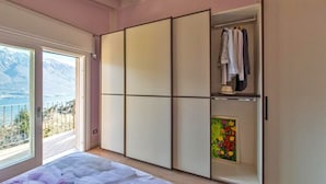 Un dormitorio con un amplio armario corredero, una cama, un cuadro y vistas a la montaña a través de una ventana.