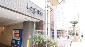 Exterior de la estación Legatio East, con una máquina expendedora y fachada de ladrillo.