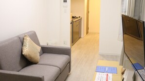 Una sala de estar moderna con un sofá gris, una mesita de madera y un televisor de pantalla plana montado en la pared.