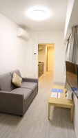 Una sala de estar moderna con un sofá gris, una mesita de madera y un televisor de pantalla plana montado en la pared.