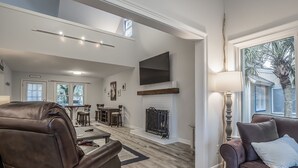 A spacious living room with a fireplace, leather sofas, and a TV mounted on the wall. - 2 BR + Loft/2BA Tarpon Pond Cottage! Great Views! Amenity access included (Seabrook Island)